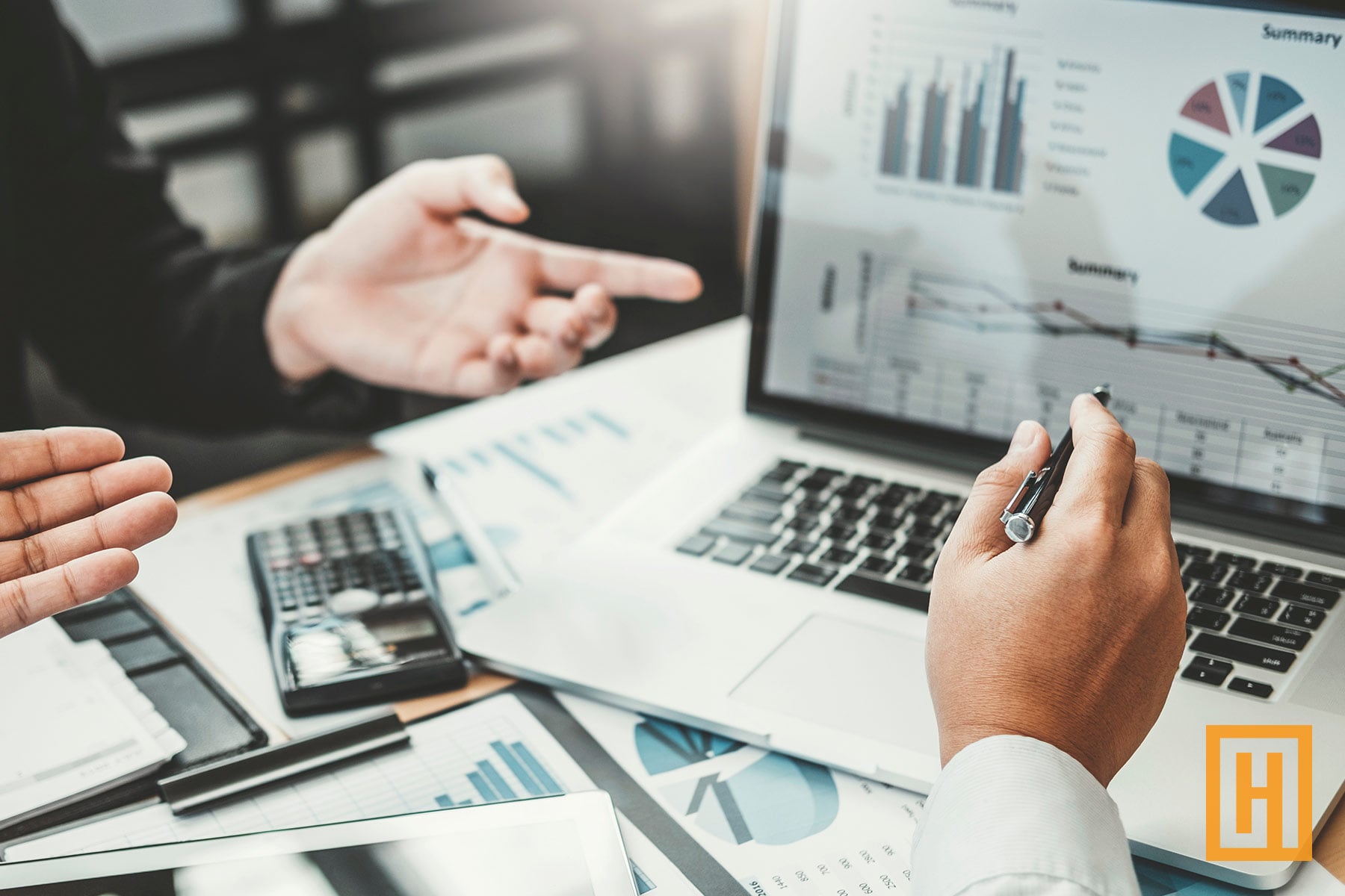 Business professionals analyzing financial reports and data visualizations on laptop and printed documents